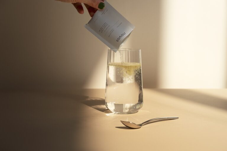 NOVOS Core powdered supplement being poured into a glass of water