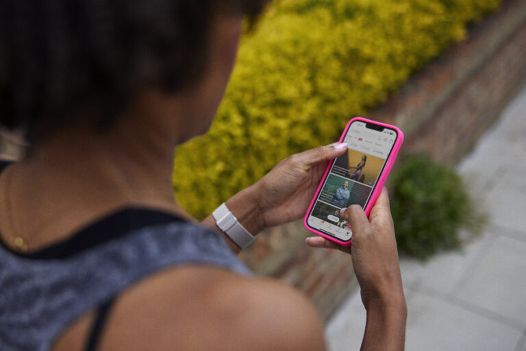 Woman holding a touch phone, looking at the Peloton app