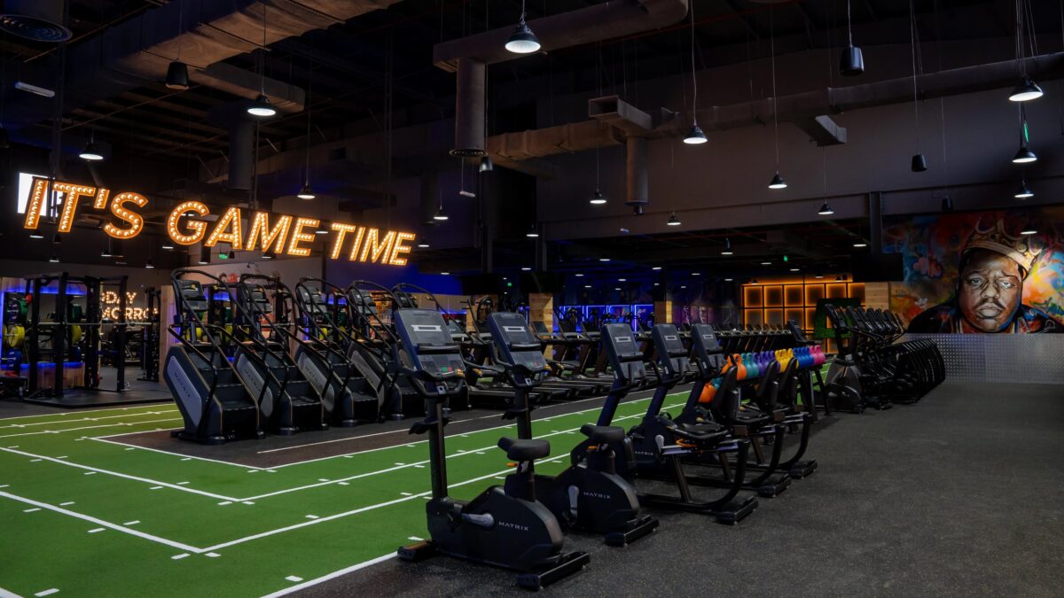 Interior of a Gymnation facility featuring a line of stationary bikes and turf