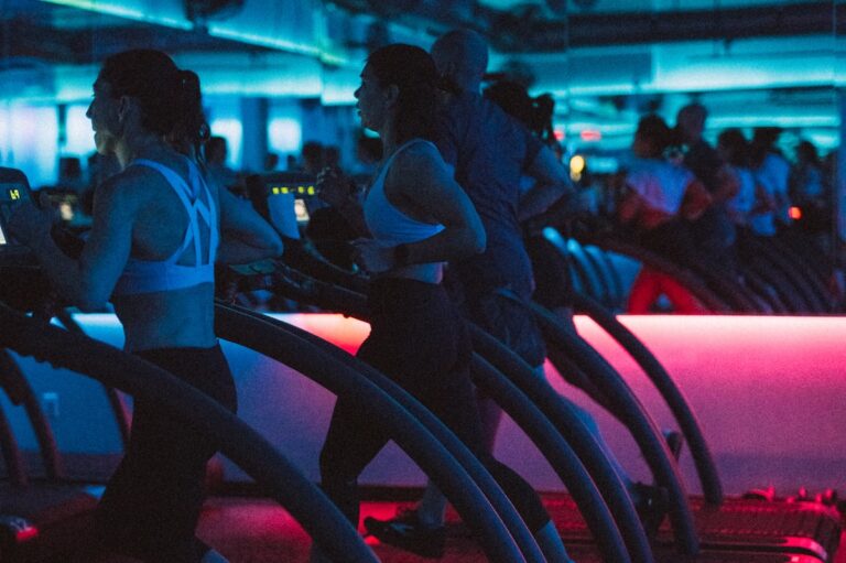Three runners on treadmills in a low-lit room