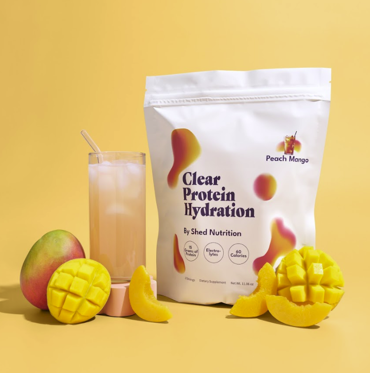Product image of ShedRX's Clear Protein Hydration supplement, with a drinking glass and mixed fruits