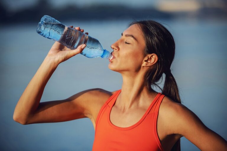 Profile of woman in activewear drinking from a plastic water bottle