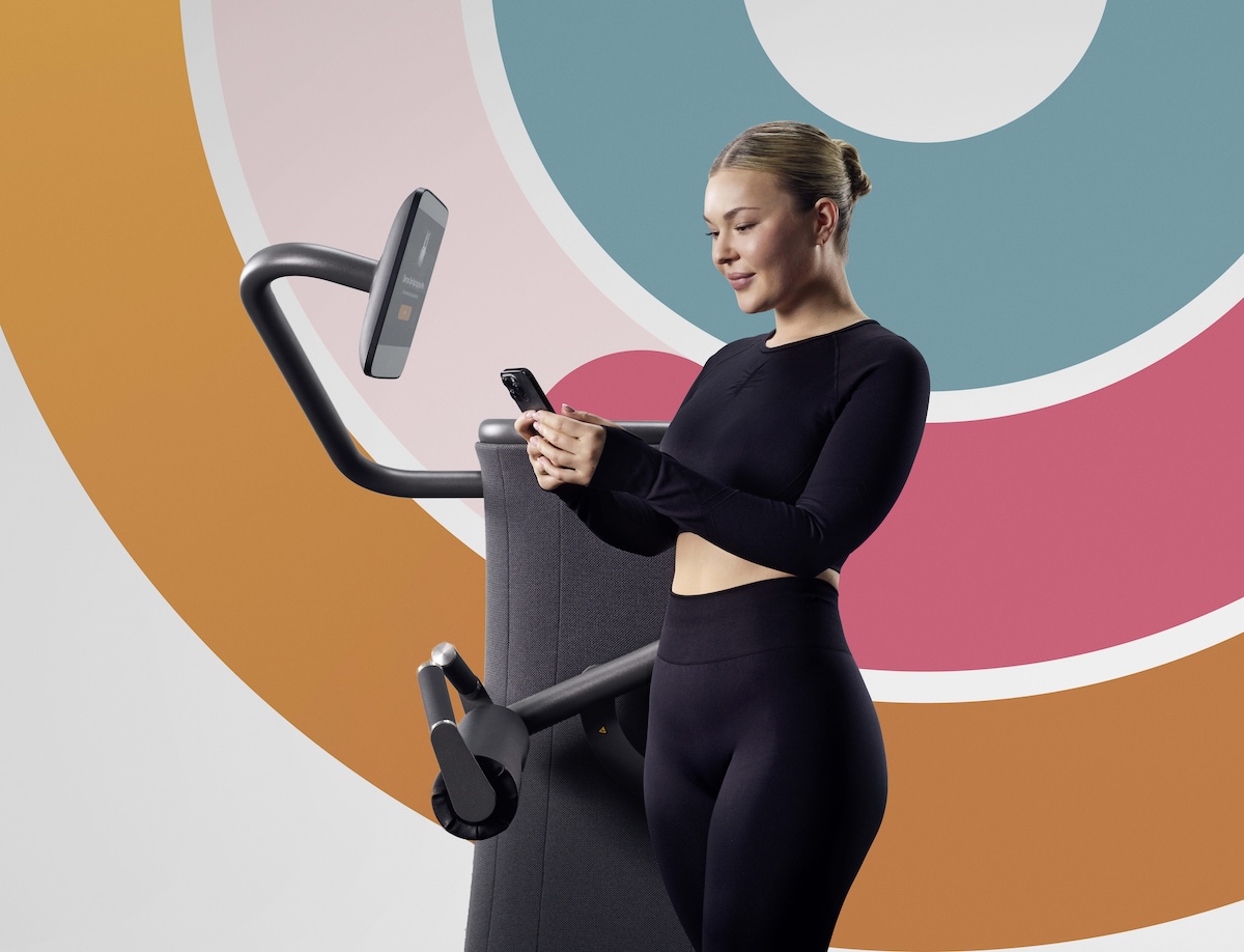 A woman in activewear on her phone next to a fitness machine