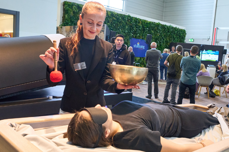 A woman is performing touchless therapy on another woman who is lying down with an eye mask on