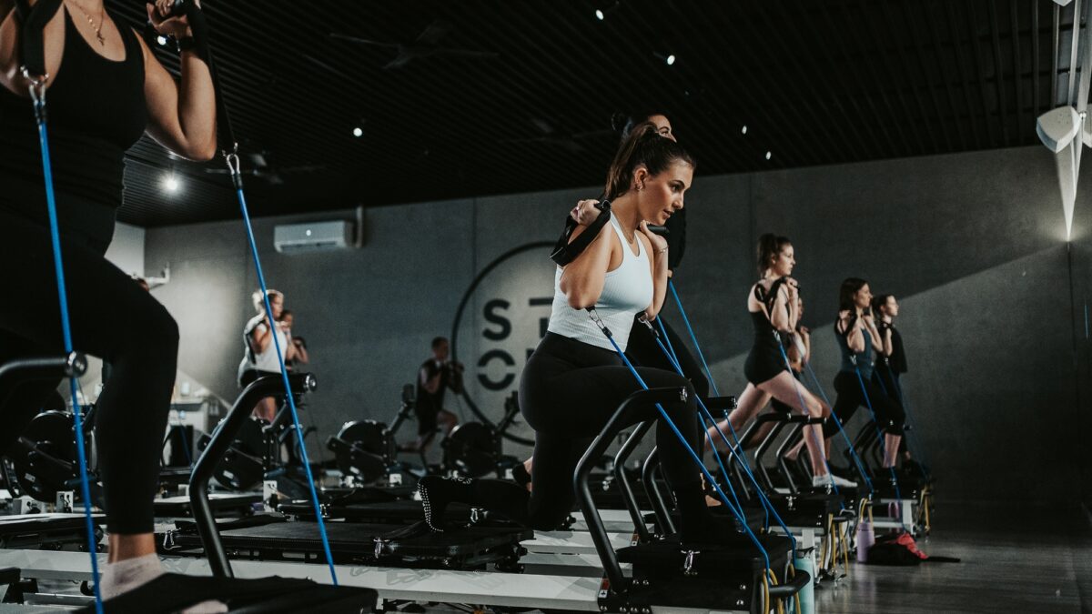 A woman performing pilates using a reformer in a dimly lit room
