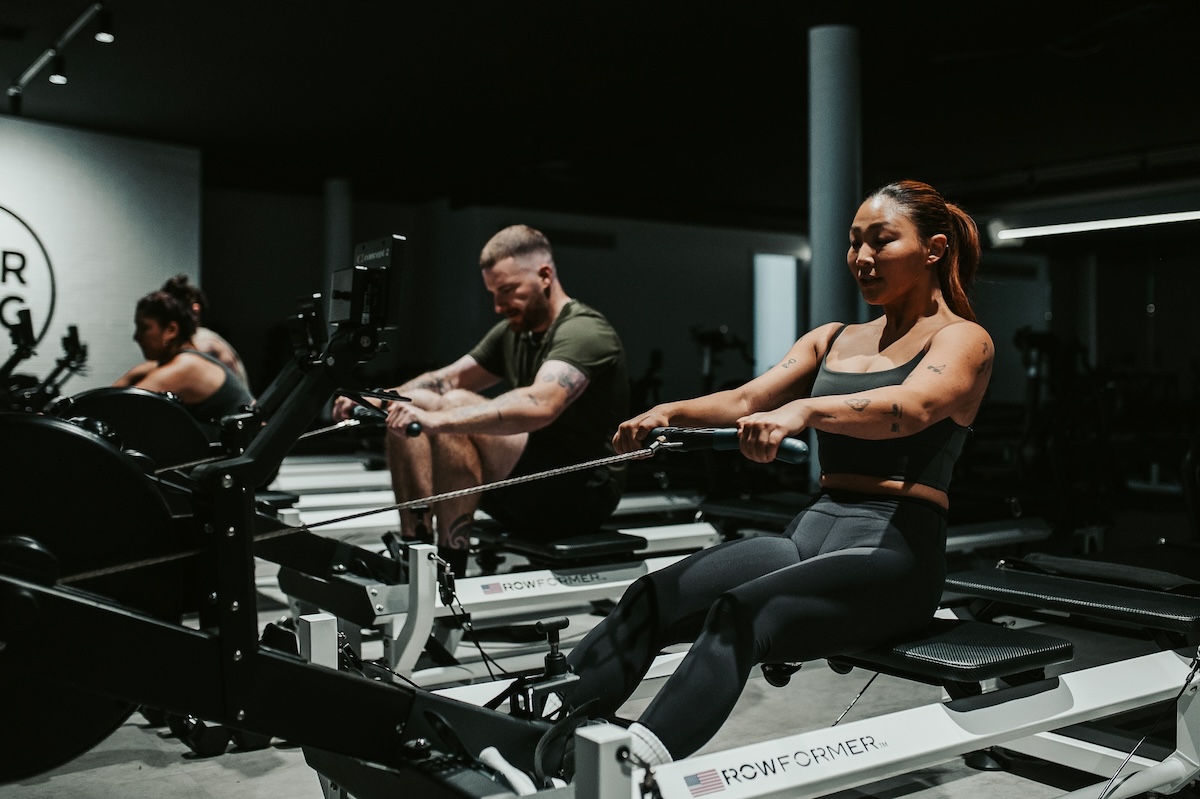 A women using a rowing machine in a dimly lit fitness studio