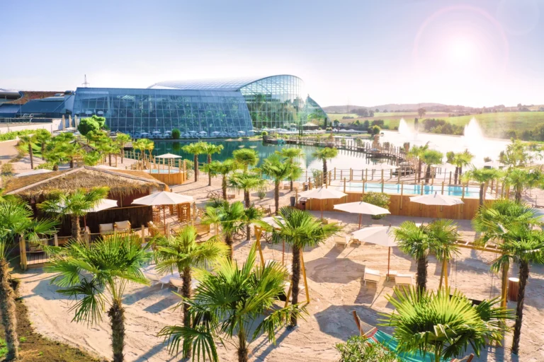 Exterior of Thermen & Badewelt Sinsheim's resort, featuring palm trees and beach chairs