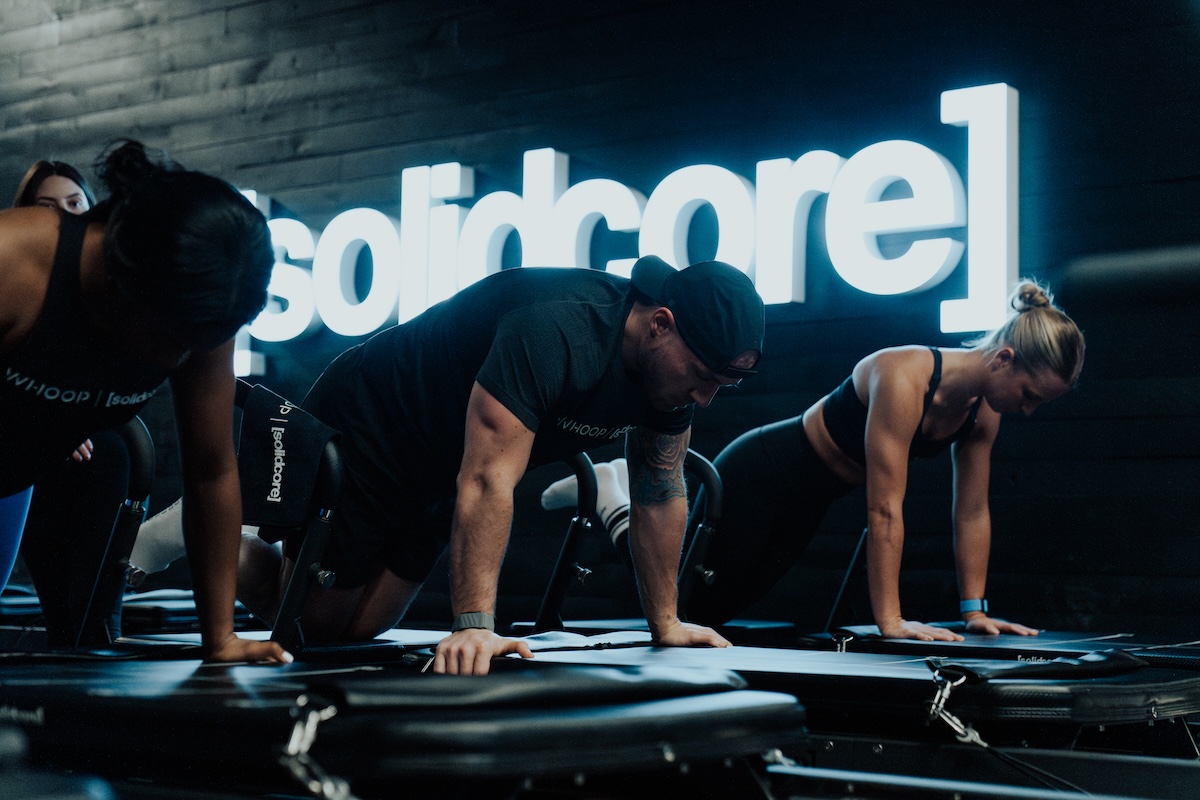 Group of people performing a plank on a reformer machine