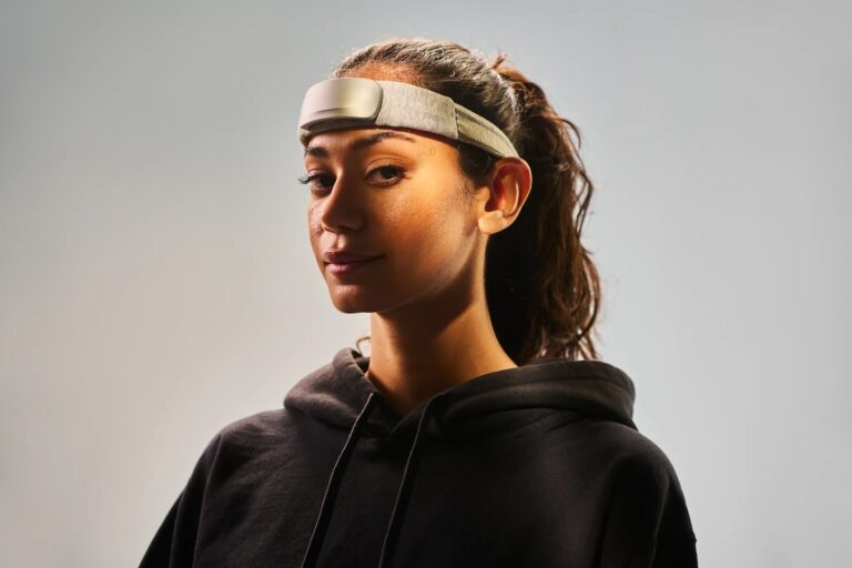 A woman wearing a black hoodie with a neurofeedback headband around her forehead