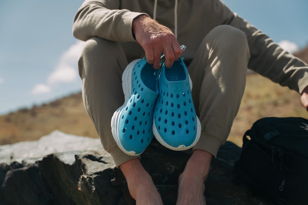 A person holding blue KANE recovery shoes
