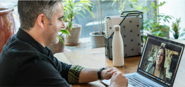 A man is talking to a woman on his laptop