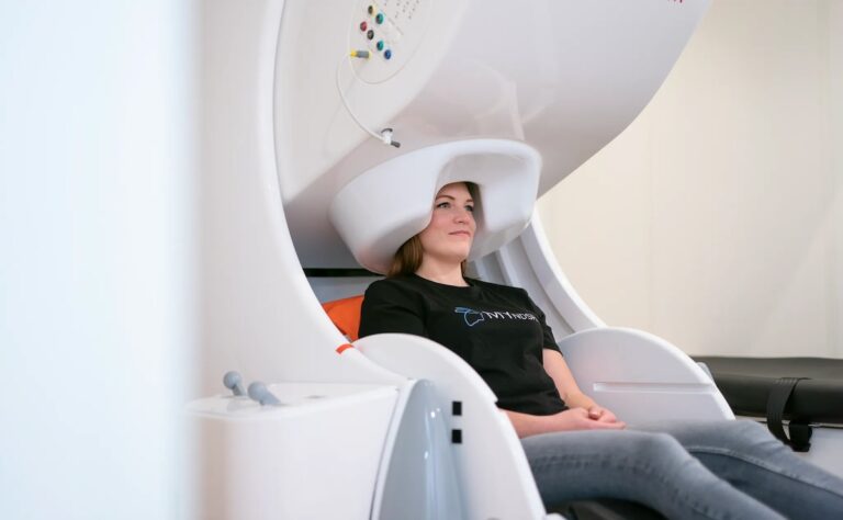 A woman sitting under a brain scanner