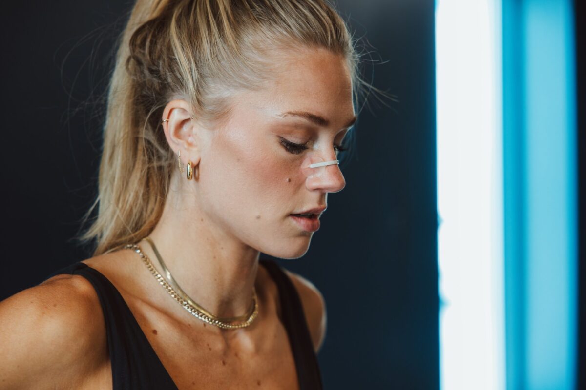 A fit woman looking down with a nasal strip on her nose