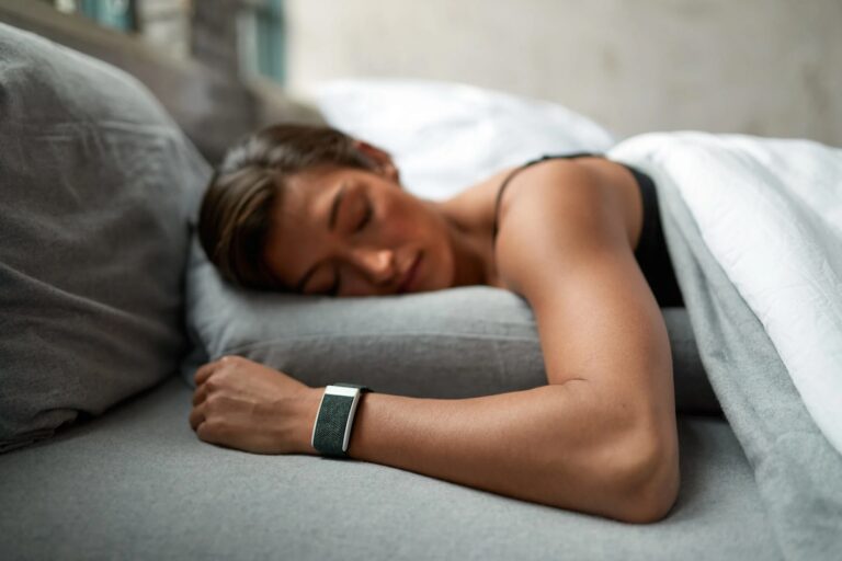 A woman sleeping in bed with a health tracking watch on her wrist
