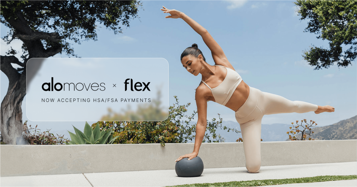 A fit woman performing a Pilates move with a small ball on a yoga mat