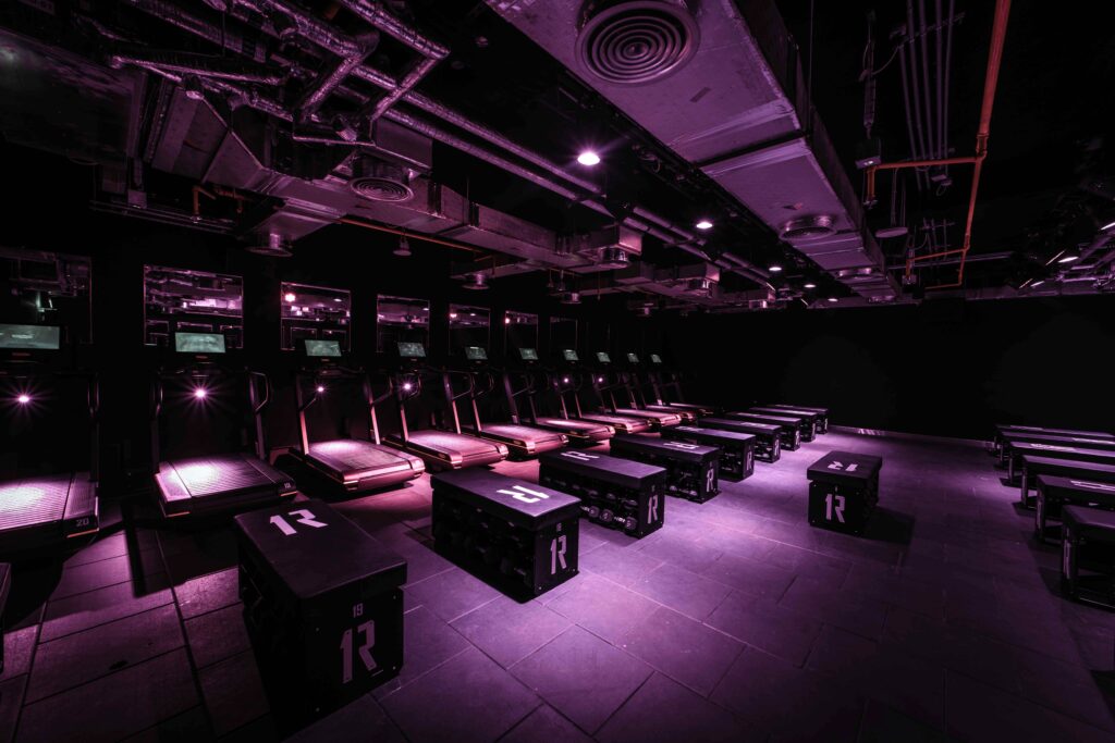 Dark lit workout room with treadmills and hiit equipment