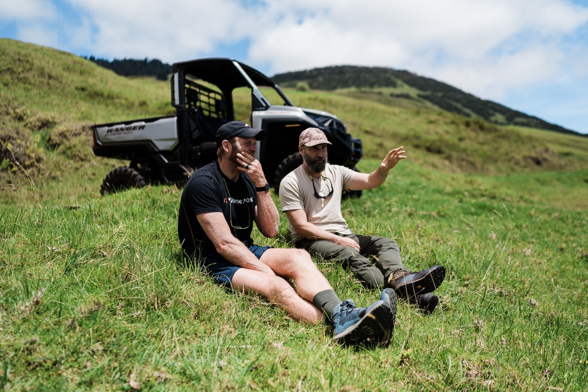 Two men sitting leisurely on grass outside