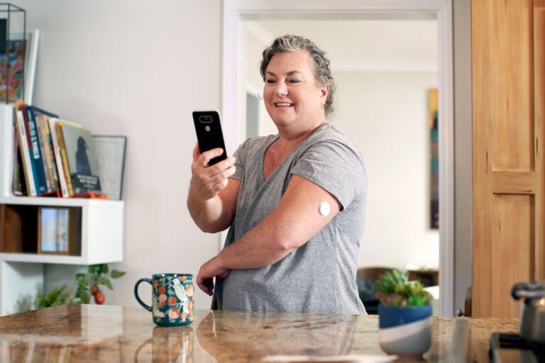 A woman with a CGM on her arm on a face call on her phone