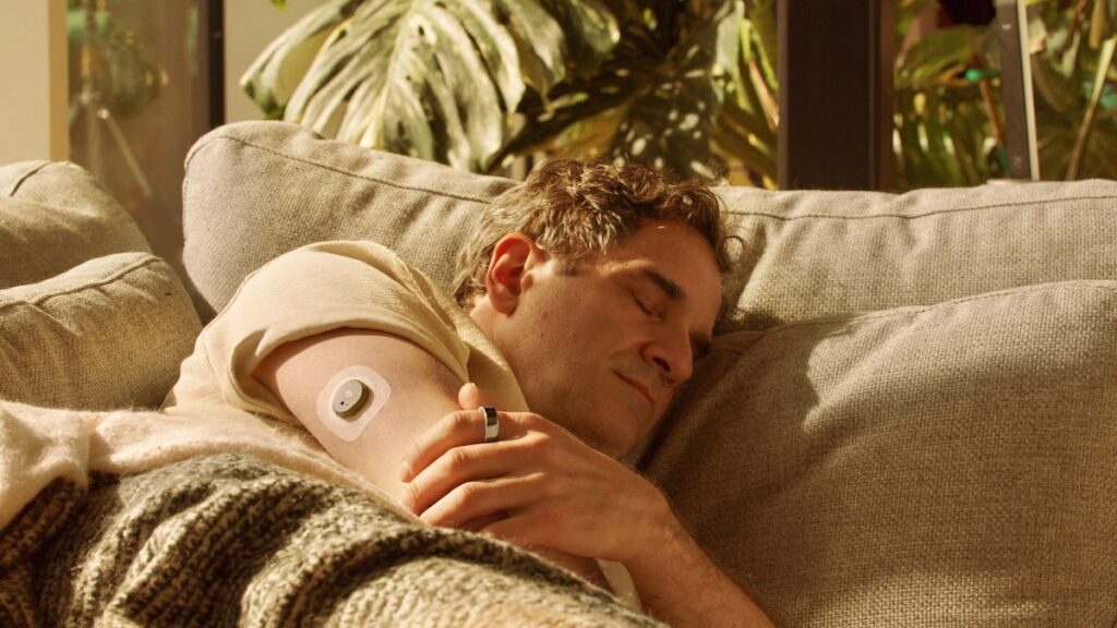 A man sleeping with an Oura ring on his finger and a dexcom CGM on his upper arm