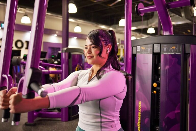 A young woman is performing a chest exercise on Planet Fitness equipment