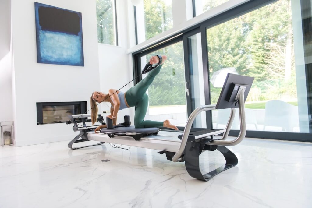 A fit woman performing a Pilates exercise on a reformer machine
