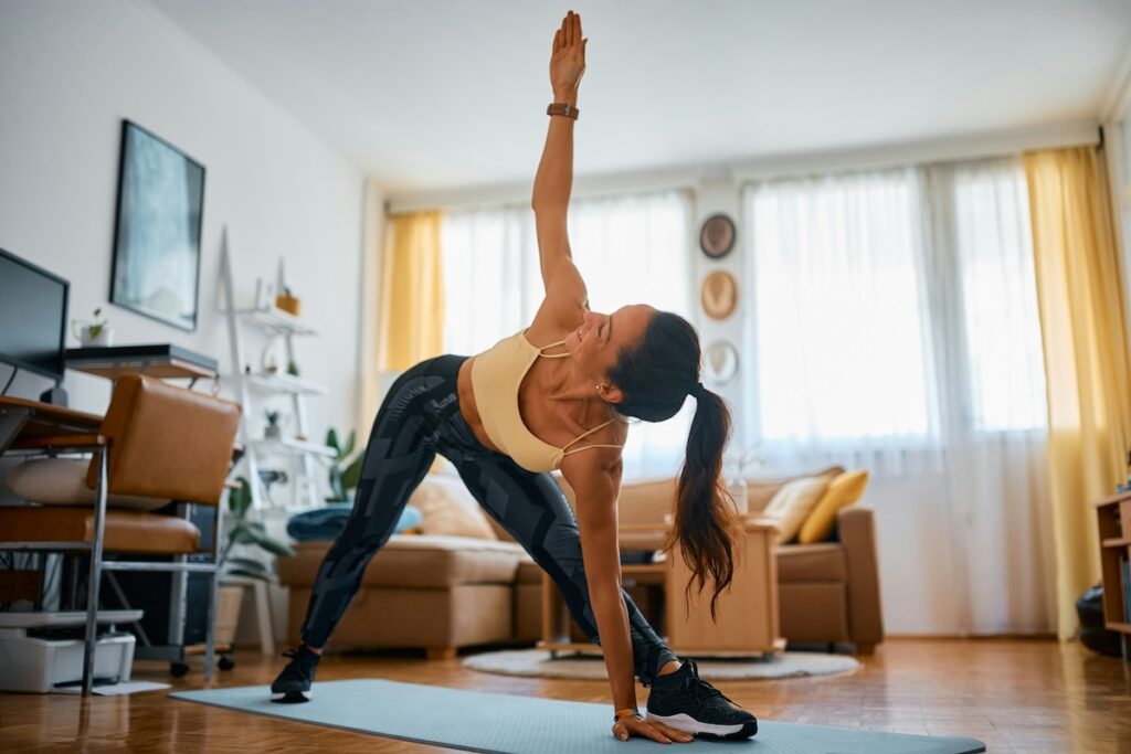 Happy athletic woman doing stretching exercises while at home