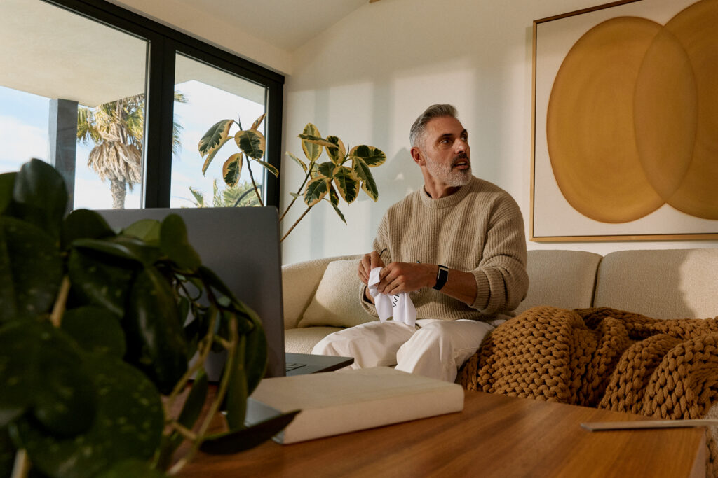 A man is sitting at home with a WHOOP watch on his wrist