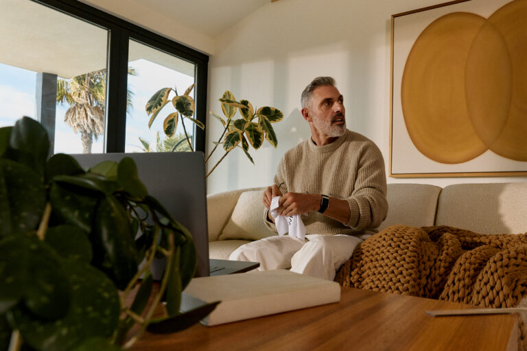 A man is sitting at home with a WHOOP watch on his wrist