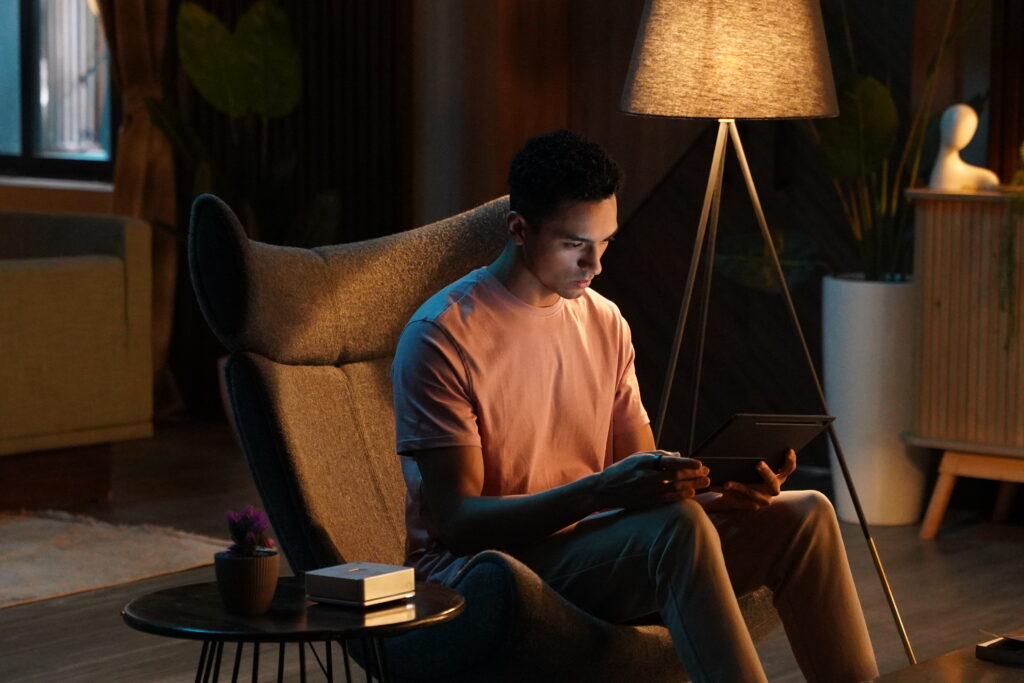 A teenage boy on a chair at home with an Ultrahuman sensor on the table