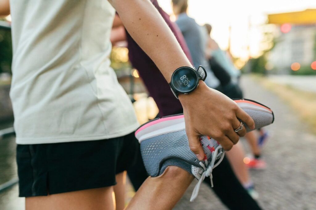 A female runner performing a quad stretch with a Samsung Galaxy Watch on her wrist