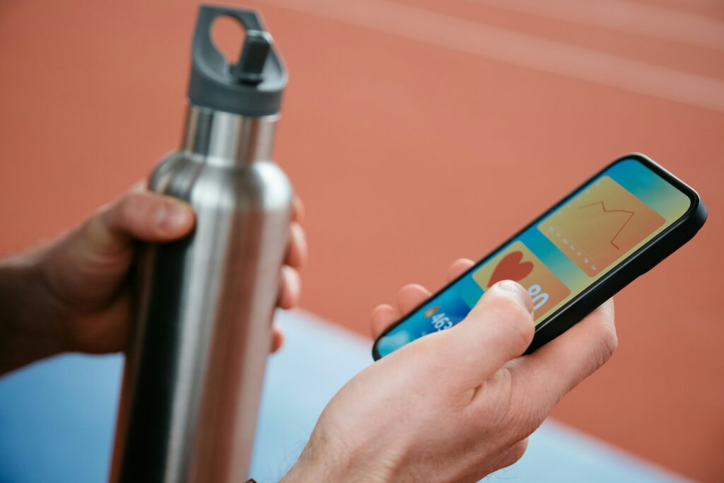 A person holding a cell phone near a water bottle