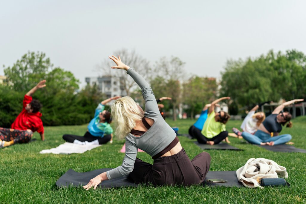 A woman seated, leading an outdoor yoga class