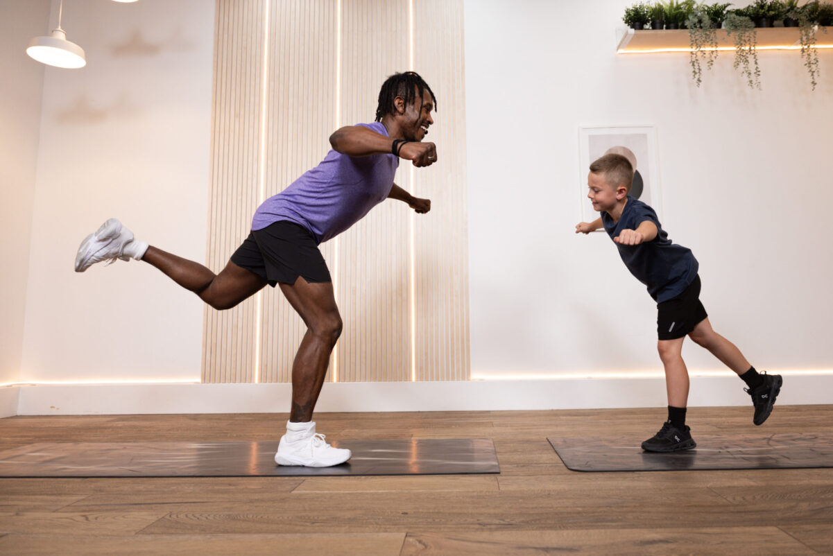 An adult and child performing a balance exercise at home