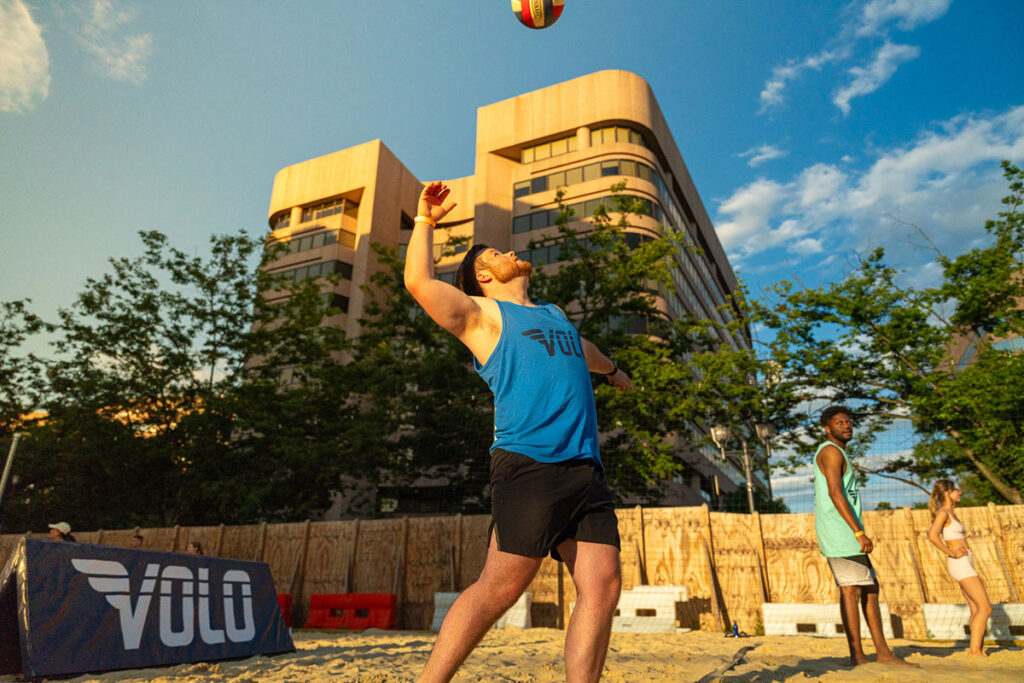 A man jumping up to serve a volleyball