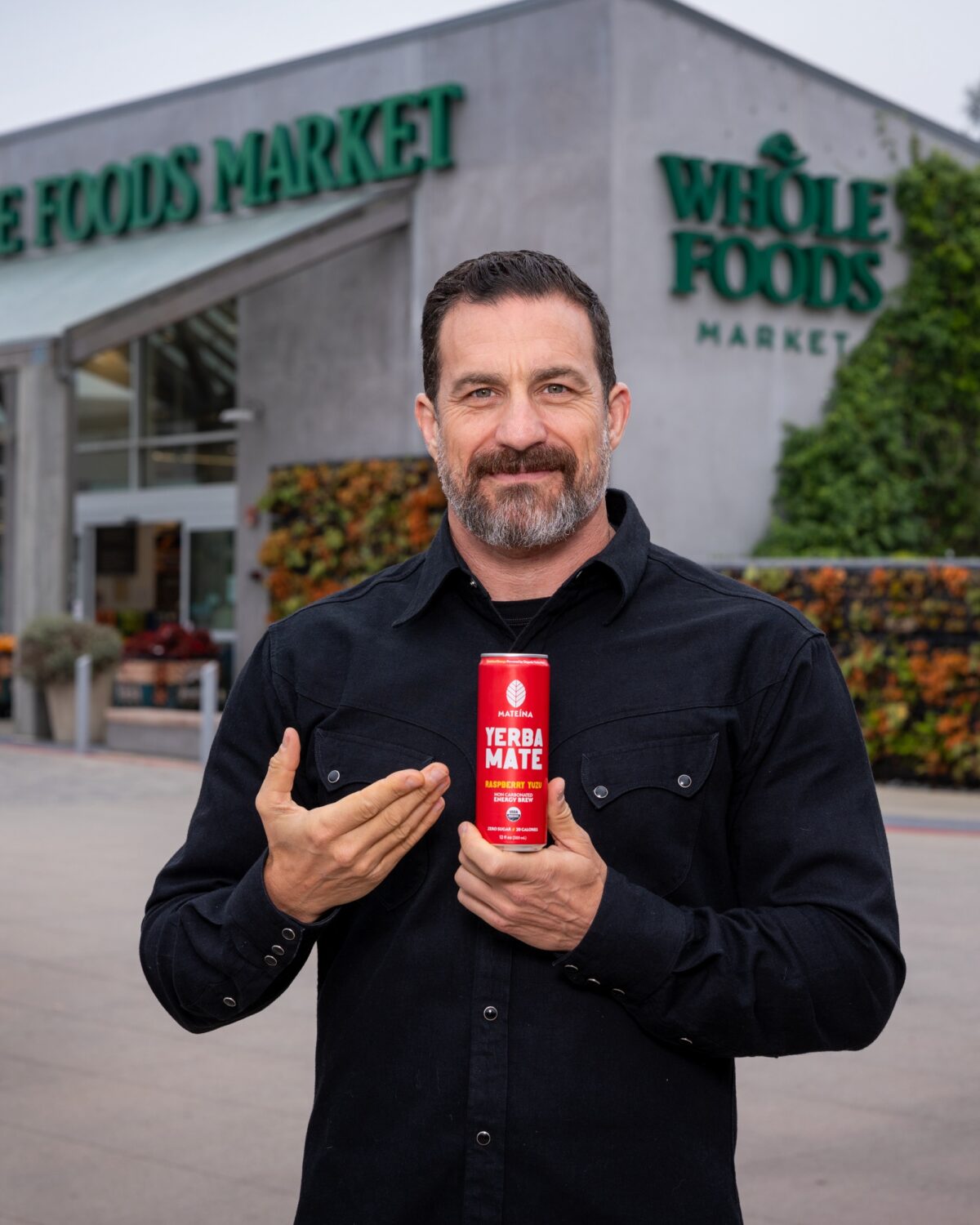 Dr. Andrew Huberman holding a can of Yerba Mate outside of Whole Foods Market