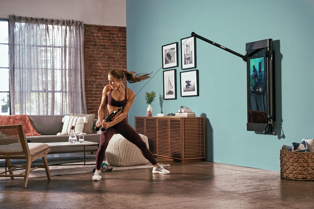 Woman performing a standing twist exercise using Tonal in her apartment