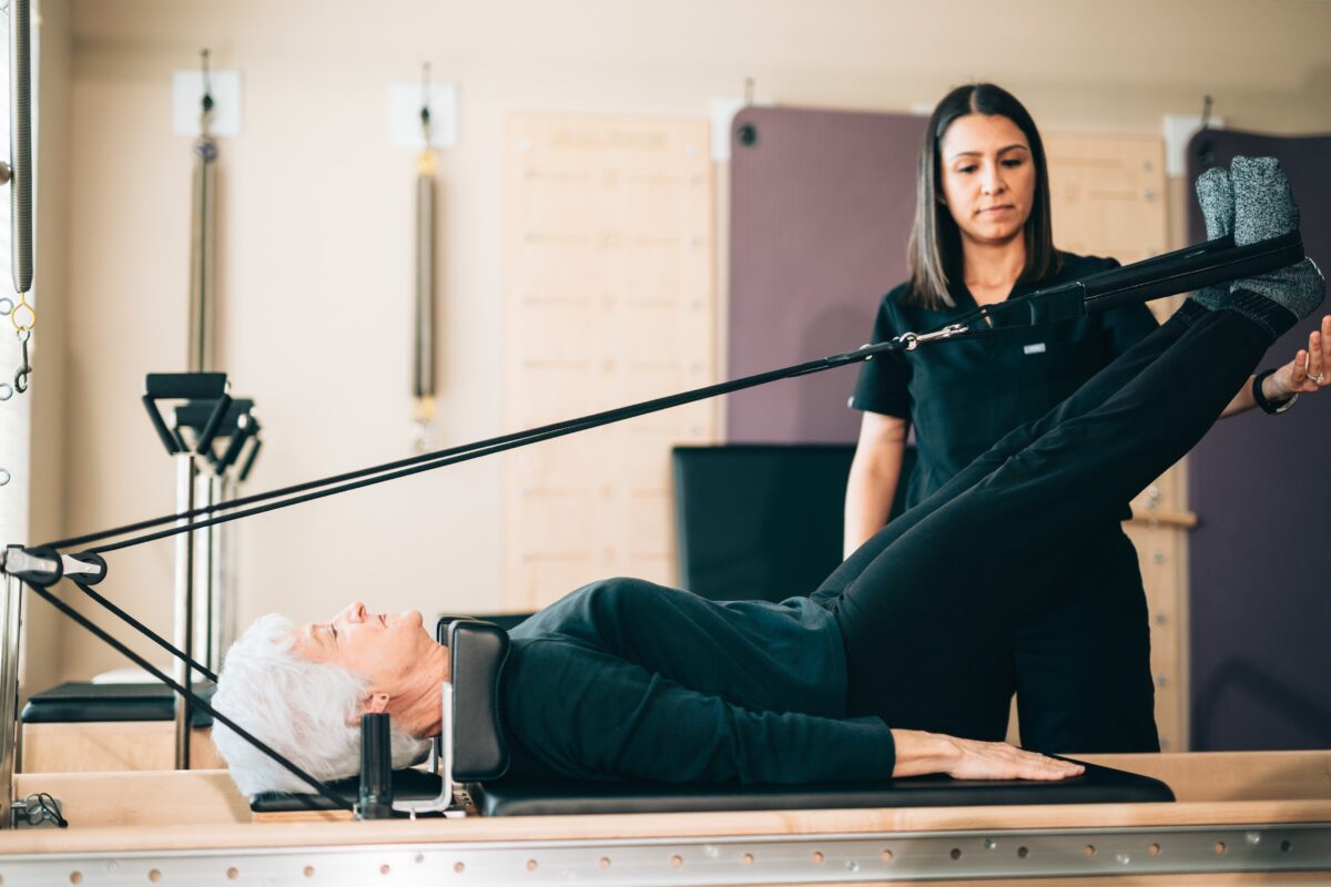 Older women performing a lower body exercise on a Pilates reformer
