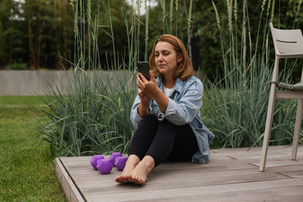 A woman on her phone with light weights by her side