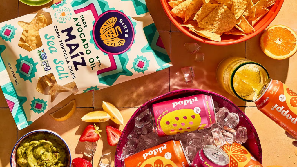 Snack table with Siete Foods chips and Poppi cans
