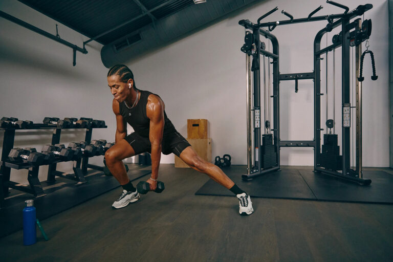 Athletic man performing a side lunge with dumbbells