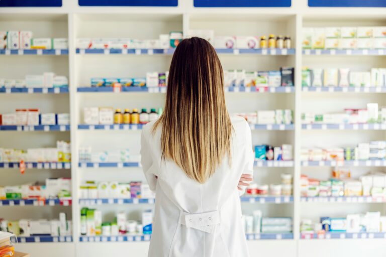 Pharmacist standing in front of medications