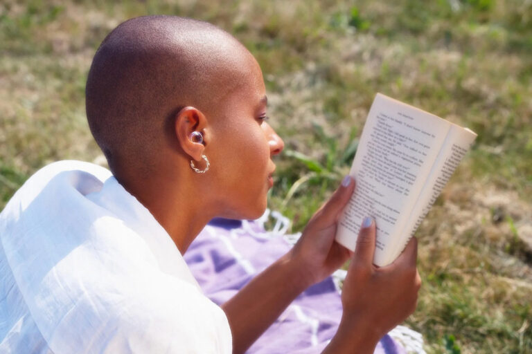 Woman wearing Loop Earplugs while reading outside