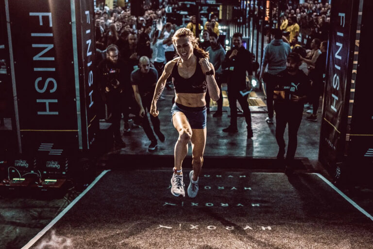 Woman crossing the finish line at a HYROX competition