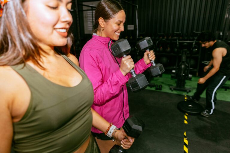 Two women lifting dumbbells in a gym