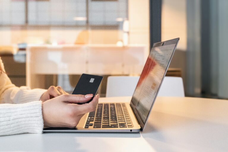 A woman sitting in front of a laptop holding a credit card