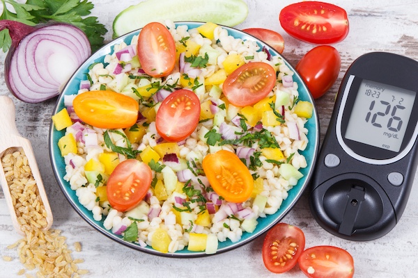 Colorful salad with tomatoes and onions, and glucometer