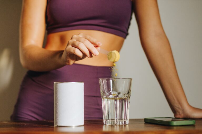 Woman scooping powdered supplement into a glass of water