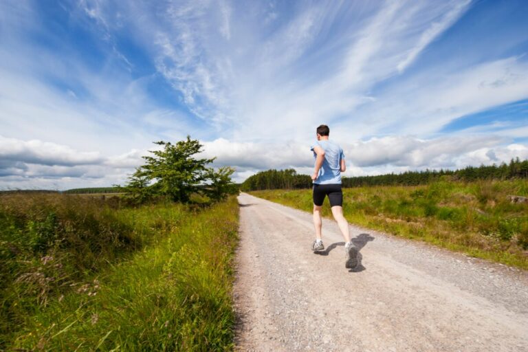 Man running on road near grass hill